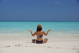 bikini woman sitting on beach doing yoga
